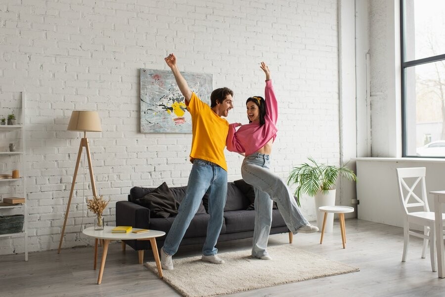 A couple dancing in a living room area.